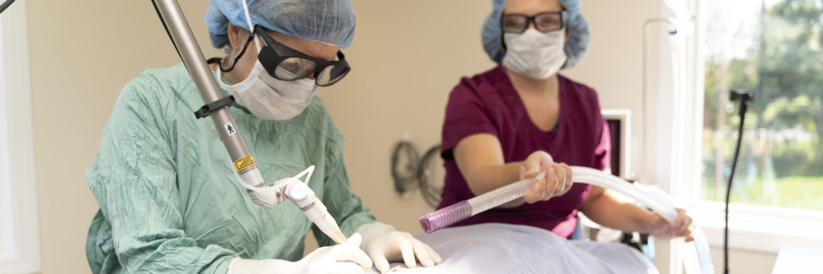 Staff member and veterinarian performing surgery in operating room.